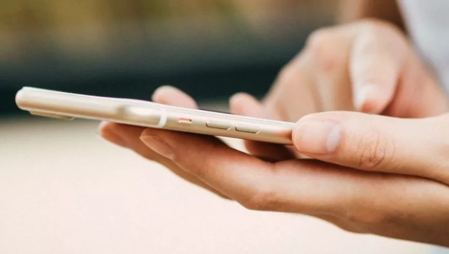 Hände halten ein Smartphone, über welches sich Sonnenschutztechnik fernsteuern lässt