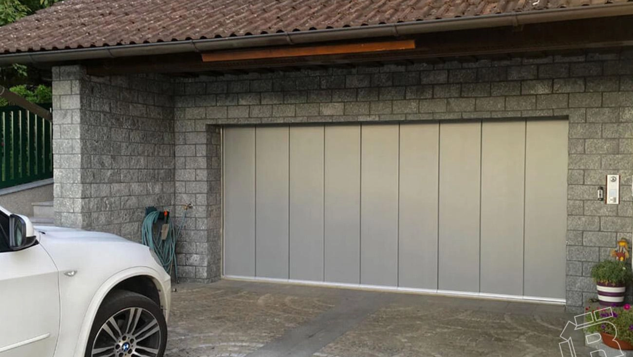 Silbriges Seitenlauftor in Garage aus grauen Steinen